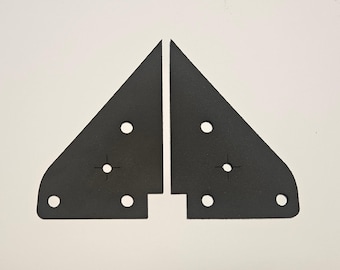 May include: Two black, triangular metal brackets with rounded corners and multiple circular holes. Each bracket has a crosshair marking near the center. The brackets are displayed against a white background.