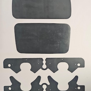 May include: An assortment of dark gray, rectangular and uniquely shaped rubber or plastic components. The image shows two large, rounded-corner rectangles and four intricately cut pieces with holes and curved edges, likely for industrial or mechanical use.