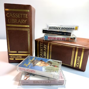 May include: Two brown faux-leather cassette library storage cases with gold lettering and trim, accompanied by five music cassette tapes featuring Frank Sinatra, Kenny Rogers, Patsy Cline, and Dottie West in their original clear plastic cases.