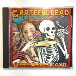 May include: A CD case featuring the album "The Best of Grateful Dead: Skeletons from the Closet." The cover art includes illustrations of a woman, a skeleton, and a cartoon figure. The album title is in yellow, and the background is red.