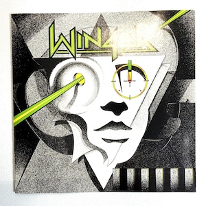 May include: Album cover art featuring a stylized face with geometric shapes and the word "WIN" in green and white. The design includes a target-like symbol and a green laser beam. The background is black and gray.
