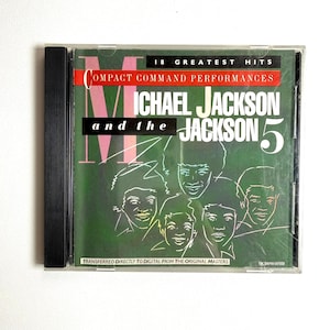 May include: A CD case featuring the album "18 Greatest Hits: Compact Command Performances" by Michael Jackson and The Jackson 5. The cover has a green background with the band members' faces and the album title in white.