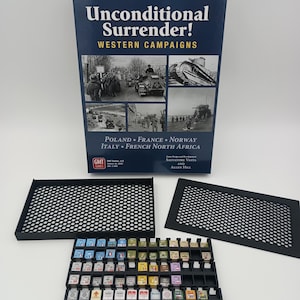 May include: A board game box titled "Unconditional Surrender! WESTERN CAMPAIGNS" with images of historical battles. Includes black plastic trays and numerous game pieces with various symbols and colors, designed for strategic gameplay.