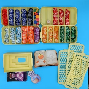 以下が含まれることがあります： トークン、サイコロ、カードなど、さまざまなコンポーネントを備えたボードゲームセット。トークンは赤、青、オレンジ、緑など複数の色があります。ゲームにはイラスト付きの小さな本と黄色の収納ボックスも含まれています。背景は単色の青です。