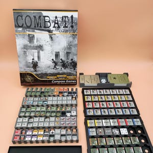 May include: A board game titled "COMBAT! Volume 1" with a black and white image of soldiers in action. The game includes various game pieces, dice, and trays for organization. The game pieces are small, with detailed graphics.