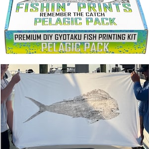 May include: A box with the text "FISHIN' PRINTS" and "PELAGIC PACK" is shown. A large white cloth is held up, displaying a detailed fish print. The print is a grayscale image of a fish. The kit is a Premium DIY Gyotaku Fish Printing Kit.