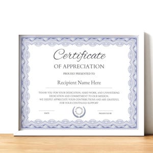 Może przedstawiać: Oprawiony certyfikat uznania z białą obwódką. Certyfikat ma niebieską ozdobną obwódkę i tekst "Certificate of Appreciation" i "Recipient Name Here". Certyfikat znajduje się na drewnianej powierzchni.