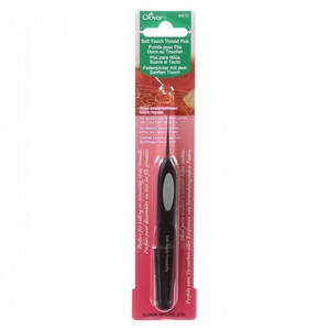May include: A black plastic thread pick with a gray handle. The packaging is pink and white and features the text "Soft Touch Thread Pick" in multiple languages.