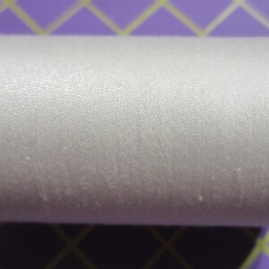 May include: A spool of white thread with light blue end caps. The thread is tightly wound and has a slightly shiny appearance. The spool is designed for sewing and crafting projects.