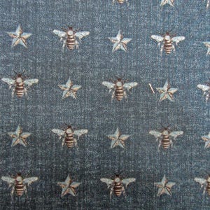 May include: A blue fabric with a repeating pattern of white stars and brown bees.