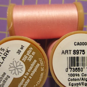 May include: A spool of pink Coats & Clark machine quilting thread. The label reads "30 wt 350 yds/v 320 m" and "Machine Quilting". The spool also has a barcode and the text "CA00011 ART 8975 K2 1210 0 73650 79363 9 100% Cotton/Coton/Algodan Egypt/Egypte/"