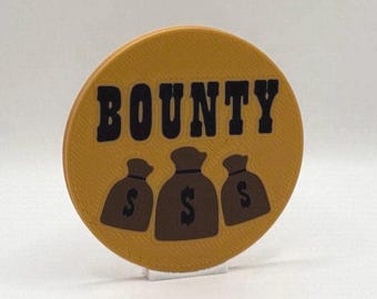 Op de afbeelding: Een rond, mosterdgeel object met het woord "BOUNTY" in zwarte blokletters. Daaronder drie bruine geldbuidels, elk met een dollarteken. Het object is lichtjes schuin.