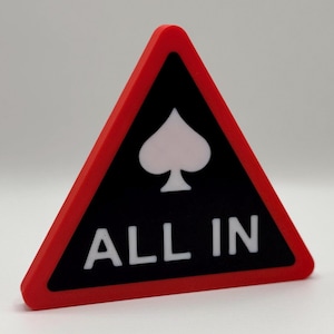 May include: A red, black, and white triangular sign with the words "ALL IN" in white block letters. The sign features a white spade symbol on a black background, framed by a red border. This item is likely related to poker or gambling.