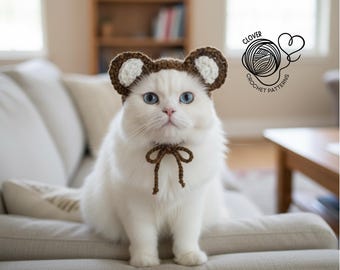 May include: A white cat with blue eyes, wearing a brown crocheted bear ear hat and a matching bow tie. The cat is seated on a light-coloured sofa. The image includes the text "CLOVER CROCHET PATTERNS".