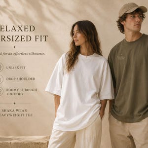 May include: A white and an olive green heavyweight t-shirt with a relaxed, oversized fit, drop shoulders, and a roomy body. The text on the image reads: RELAXED OVERSIZED FIT, Designed for an effortless silhouette, UNISEX FIT, DROP SHOULDER, ROOMY THROUGH THE BODY, SHAKA WEAR HEAVYWEIGHT TEE.