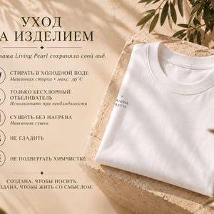 以下が含まれることがあります： 袖にPARADISE PALETTEの文字がプリントされた、折りたたまれた白いTシャツ。画像にはロシア語のケアラベルが含まれており、30度以下の冷水での洗濯、非塩素系漂白剤の使用、熱を避けた乾燥、アイロン掛け禁止、ドライクリーニング禁止を示すアイコンが表示されています。