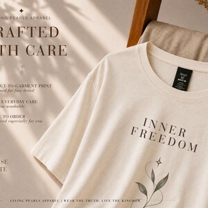 Puede incluir: Una camiseta de manga corta color crema con el texto INNER FREEDOM en una fuente serif oscura sobre un gr&aacute;fico bot&aacute;nico de l&iacute;neas finas con una estrella de cuatro puntas. La prenda tiene una etiqueta negra en el cuello y texto promocional.