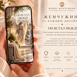 May include: A smartphone displaying a digital wallpaper of an angel standing in a classical architectural setting with the Russian text "ОН ВСТАЛ МЕЖДУ". The screen also shows Russian text and icons representing protection, grace, presence, and peace.