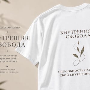 以下が含まれることがあります： 「ВНУТРЕННЯЯ СВОБОДА」および「СПОСОБНОСТЬ ОХРАНЯТЬ СВОЙ ВНУТРЕННИЙ МИР」というダークブラウンのキリル文字テキストと、葉のついた植物の茎と小さな四芒星の繊細な線画がプリントされた白いTシャツ。