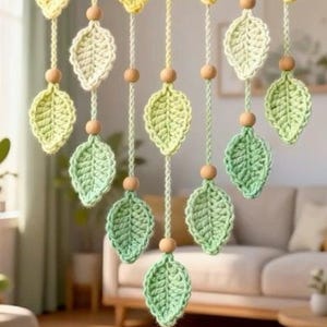 Puede incluir: Guirnalda de hojas de ganchillo hechas a mano en tonos amarillos y verdes. Cada hoja está suspendida por una cuerda con una cuenta de madera. Las hojas son de varios tonos de verde y amarillo, creando un acento decorativo natural.