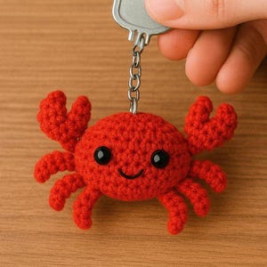 Puede incluir: Un llavero de cangrejo rojo hecho a mano con ojos negros y una boca sonriente. El cangrejo está unido a una llave plateada mediante una pequeña cadena. Un accesorio divertido.