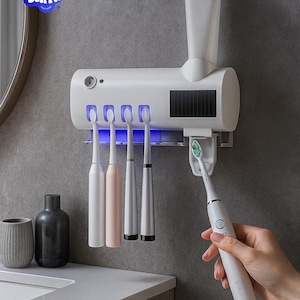 May include: A white toothbrush holder with a built-in toothpaste dispenser and UV light sanitizer. The holder has slots for four toothbrushes, with a fifth toothbrush being held by a person. The Zekyr logo is visible in the upper left corner.
