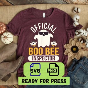 Könnte beinhalten: Ein weinrotes T-Shirt mit dem Text "OFFICIAL BOO BEE INSPECTOR" und einer Grafik eines Geistes mit Sonnenbrille. Das Shirt ist mit Kürbissen, einer Sonnenblume und einem Paar Stiefeln verziert. Ein grünes Rechteck mit "SVG"- und "PNG"-Symbolen ist ebenfalls sichtbar.