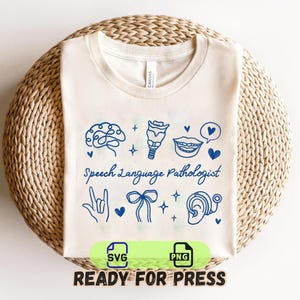 May include: Cream-colored t-shirt with blue line art illustrations of a brain, throat, lips, and other speech-related symbols. The words "Speech Language Pathologist" are written in a script font. The shirt is on a woven, circular surface.