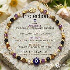 May include: A gold-colored bracelet with various gemstone beads, including amethyst, clear quartz, tiger eye, and black tourmaline. The bracelet features an evil eye charm and the word "Protection".