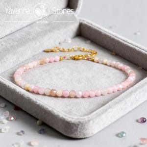 May include: A delicate pink gemstone bracelet with a gold chain clasp, displayed in a gray velvet jewelry box. The bracelet features small, faceted pink beads. The Yavanna Stones logo is visible in the top left corner.