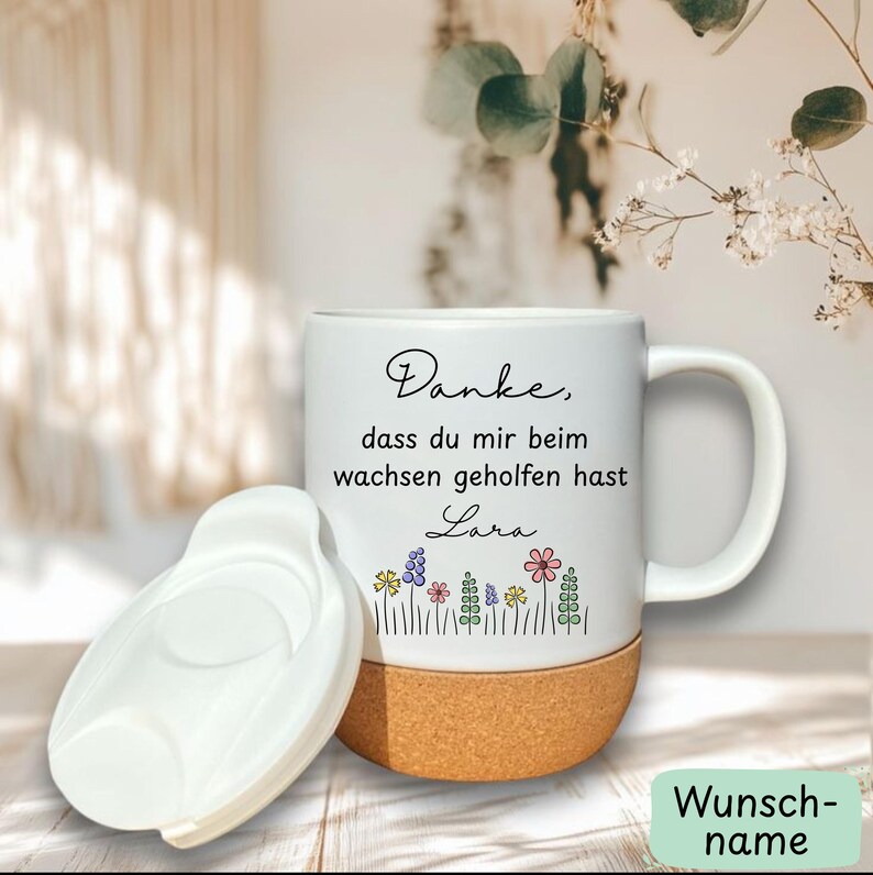 May include: White ceramic mug with a cork base and a white lid. The mug features a floral design and text that reads "Danke, dass du mir beim wachsen geholfen hast Lara."