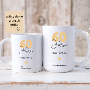 May include: Two white ceramic mugs with a yellow "60 Jahre" design and "Happy Birthday" text. One mug has "Jeanne" and the other has "Susanne" written below. The mugs have a heart graphic and are for a 60th birthday.