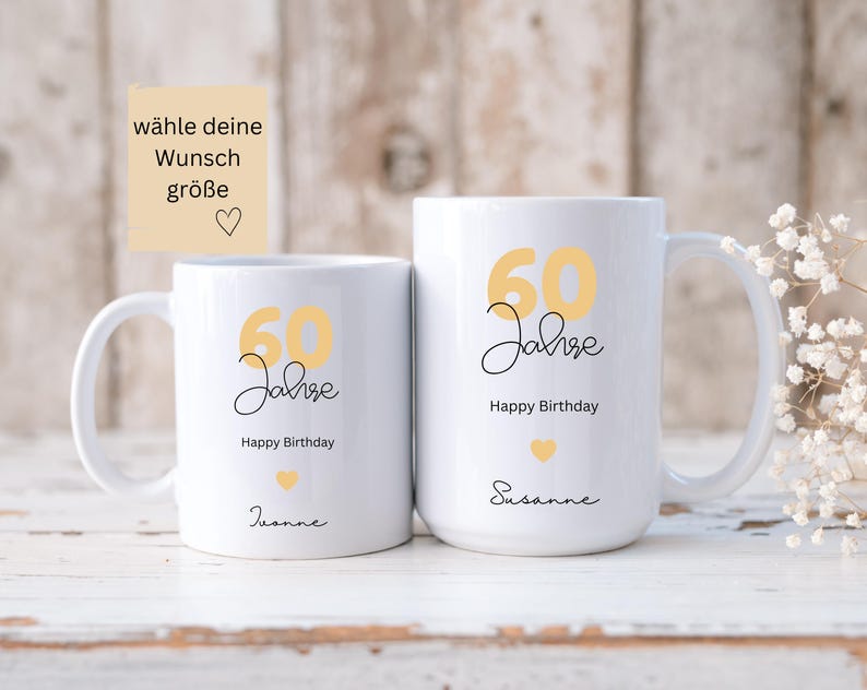 May include: Two white ceramic mugs with a yellow "60 Jahre" design and "Happy Birthday" text. One mug has "Jeanne" and the other has "Susanne" written below. The mugs have a heart graphic and are for a 60th birthday.