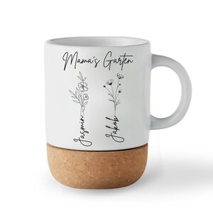 May include: White ceramic mug with a cork base. The mug features the text "Mama's Garten" and the names "Jasmin" and "Jakob" with floral illustrations. The handle is white.