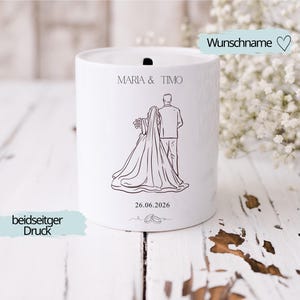 Puede incluir: Recuerdo de boda de cer&aacute;mica blanca con un dibujo lineal negro de una novia y un novio. Los nombres "Maria & Timo" y la fecha "26.06.2026" est&aacute;n impresos. Las palabras "Wunschname" y "beidseitger Druck" tambi&eacute;n son visibles.