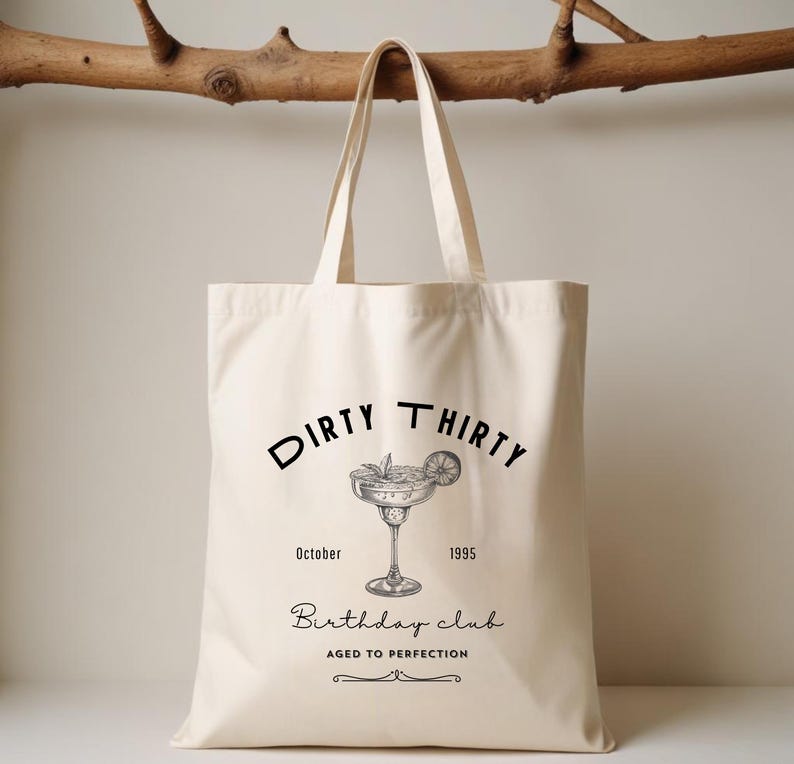 May include: Cream-colored tote bag with black text and a cocktail illustration. The text reads "Dirty Thirty" above a margarita glass, with "October 1995" and "Birthday Club Aged to Perfection" below.