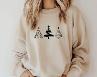 May include: A beige sweatshirt featuring three black Christmas tree designs. The trees are stylized with varying patterns, including swirls, lines, and zigzags, each topped with a star. The sweatshirt has a crew neck and long sleeves.