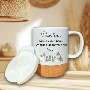 May include: White ceramic mug with a cork base and a white lid. The mug features the text "Danke, dass du mir beim wachsen geholfen hast Lara" and a floral design in various colors. The mug has a handle.