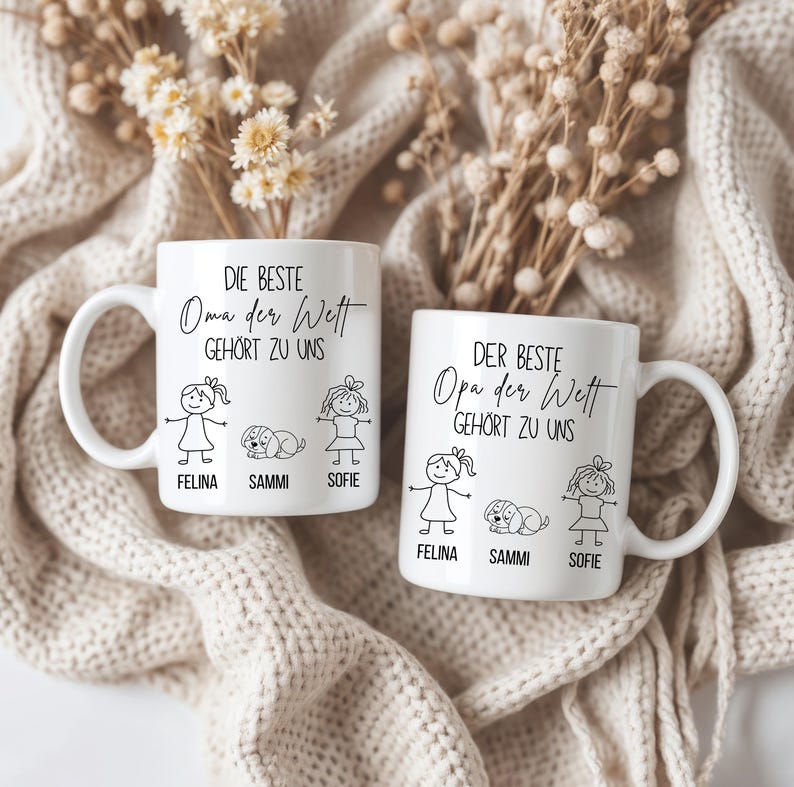May include: Two white ceramic mugs with black text and illustrations. One mug says "DIE BESTE Oma der Wett GEH&Ouml;RT ZU UNS" with stick figures and the names Felina, Sammi, and Sofie. The other mug says "DER BESTE Opa der Wett GEH&Ouml;RT ZU UNS".