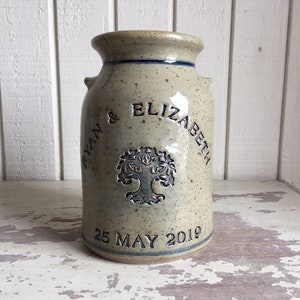 May include: A beige ceramic vase with a tree design and the text "Ryan & Elizabeth 25 May 2019".