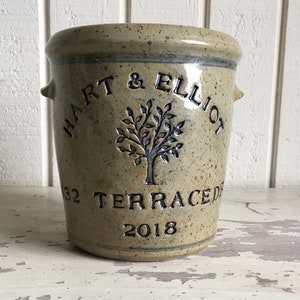 May include: A beige ceramic jar with a tree design and the text "HART & ELLIOT 32 TERRACE DR 2018" in black.