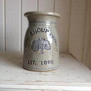 May include: A ceramic vase with a speckled glaze in shades of grey and white. It features a blue and white design with the text "The Shoup Family Est. 1999" and a stylised tree.