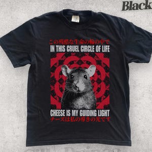 Könnte beinhalten: Schwarzes T-Shirt mit einer Ratten-Grafik und dem Text "IN THIS CRUEL CIRCLE OF LIFE" und "CHEESE IS MY GUIDING LIGHT" auf Englisch und Japanisch. Das Design beinhaltet ein rotes und schwarzes kreisförmiges Muster.