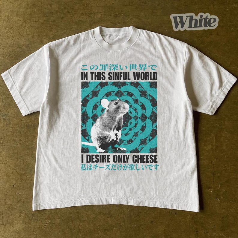Op de afbeelding: Wit t-shirt met een afbeelding van een rat en de tekst "IN THIS SINFUL WORLD" en "I DESIRE ONLY CHEESE" in het Engels en Japans. Het ontwerp heeft een turquoise en zwarte achtergrond.