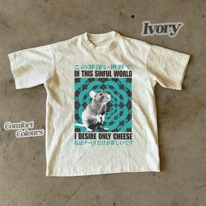 Op de afbeelding: Ivoor t-shirt met een rattenafbeelding en de tekst "IN THIS SINFUL WORLD" en "I DESIRE ONLY CHEESE". Het shirt is gemarkeerd met "Comfort Colours".