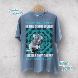 Op de afbeelding: Blauw spijkerbroek T-shirt met een rattenafbeelding en de tekst "IN THIS SINFUL WORLD" en "I DESIRE ONLY CHEESE". Het ontwerp heeft een turquoise en zwart cirkelvormig patroon. Het shirt is een comfortkleur.
