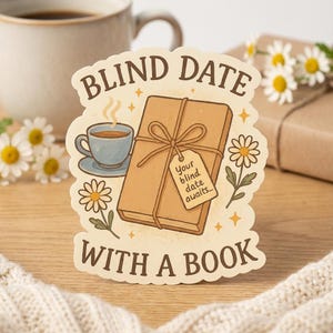 Può includere: Un adesivo con la scritta "BLIND DATE WITH A BOOK" presenta un libro avvolto con un'etichetta che recita "Your blind date awaits...". Una tazza di caffè e margherite sono anch'esse illustrate sull'adesivo. L'adesivo è su una superficie di legno.