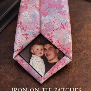May include: A pink floral patterned tie with a photo insert. The tie features a detailed design with pink, light blue, and white flowers. The text "IRON-ON TIE PATCHES" and "Personalize Your Tie with a Photo" are visible.