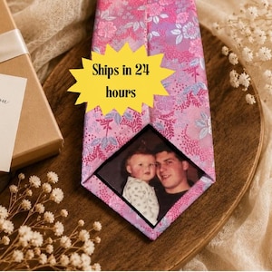 May include: A pink necktie featuring a floral pattern and a custom photo insert showing a child and an adult. A yellow star-shaped graphic with the text Ships in 24 hours is overlaid on the tie. A gift box with a white ribbon and a tag reading Thank You FOR RAISING THE MAN OF MY DREAMS is visible.