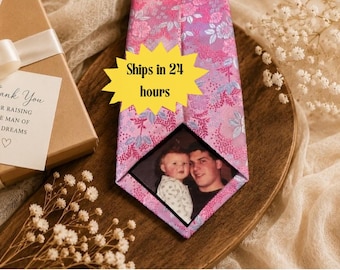 May include: A pink necktie featuring a floral pattern and a custom photo insert showing a child and an adult. A yellow star-shaped graphic with the text Ships in 24 hours is overlaid on the tie. A gift box with a white ribbon and a tag reading Thank You FOR RAISING THE MAN OF MY DREAMS is visible.